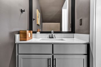 A modern bathroom with a undermount sink, framed mirror, and quartz countertops at West Row Lofts and Townhomes in Birmingham, AL.